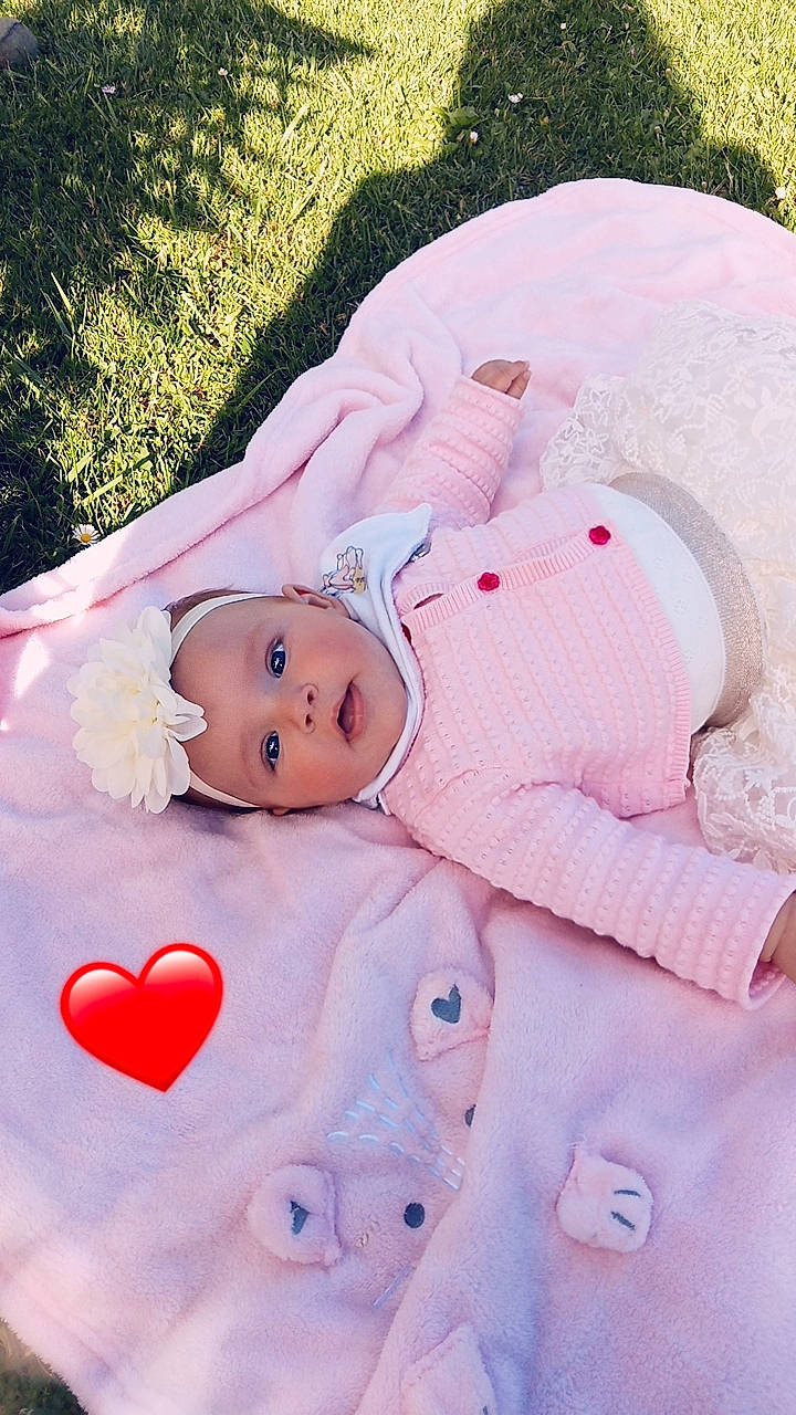 Évana a rejoint le concours — aidez-le/la à gagner de superbes lots ! baby, baby_products, baby_toddler_clothing, cheek, child, doll, grass, hand, happy, head, headgear, headwear, linens, lip, person, pink, plant, skin, stuffed_toy, textile