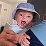 Ryder joined the competition — help win amazing prizes! baby, child, hat, bucket_hat, person, hand, adult_hand, smiling, happy, indoor, portrait, face, clothing, blue, white, skin, expression, holding, closeup, infant
