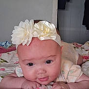 Cecilia joined the competition — help win amazing prizes! baby, infant, headband, flower, face, eyes, smile, hand, blanket, floral, bedroom, indoors, cute, child, portrait, skin, clothing, resting, lying_down, soft
