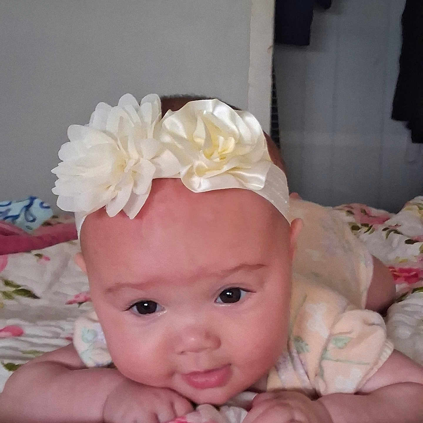 Cecilia joined the competition — help win amazing prizes! baby, infant, headband, flower, face, eyes, smile, hand, blanket, floral, bedroom, indoors, cute, child, portrait, skin, clothing, resting, lying_down, soft