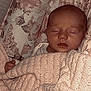 baby, sleeping, blanket, knitted, crib, cushion, floral_pattern, infant, peaceful, cozy, child, portrait, indoors, soft_lighting, resting, cute, newborn, wrapped, tender, sleep