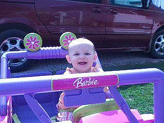 Sarah is registered to the contest to win money with this photo: alloy_wheel, automotive_design, automotive_exterior, automotive_lighting, automotive_tire, car, fender, happy, hood, joy, light, motor_vehicle, person, pink, purple, smile, tire, toddler, vehicle, vehicle_door