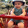 Kodah is registered to the contest to win money with this photo: toddler, child, shopping_cart, hat, striped_hat, blue_romper, flowers, baby_breath, bouquet, grocery_store, indoor, person, cute, sitting, red_cart, shoes, socks, natural_light, portrait, retail