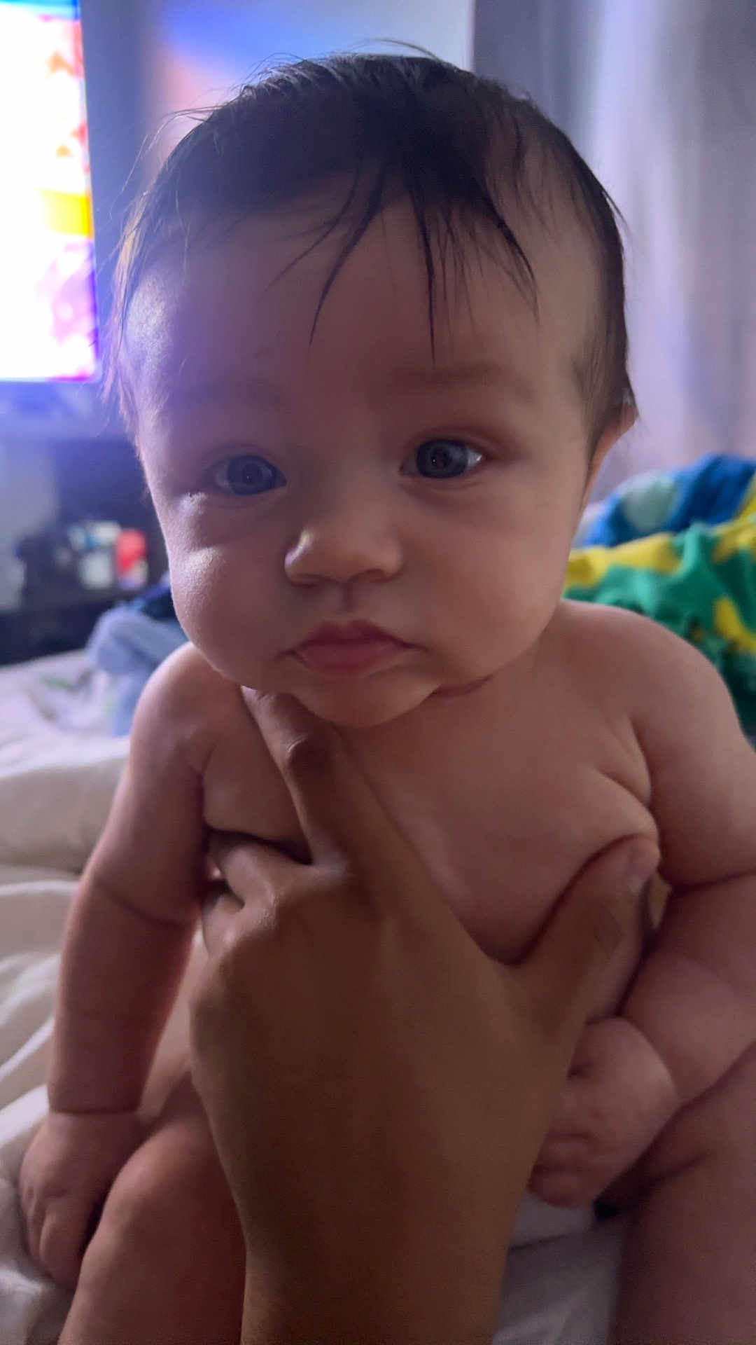 Malik joined the competition — help win amazing prizes! baby, infant, hand, face, skin, eyes, person, indoors, bed, blanket, curious, closeup, child, portrait, soft_light, human, newborn, support, sitting, young
