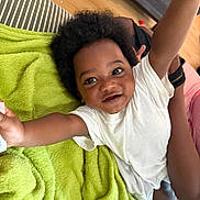 Shemar joined the competition — help win amazing prizes! toddler, child, smiling, happy, arms_up, curly_hair, white_shirt, green_blanket, striped_couch, wooden_floor, indoor, person, baby, cute, playful, face, skin, expression, joy, home