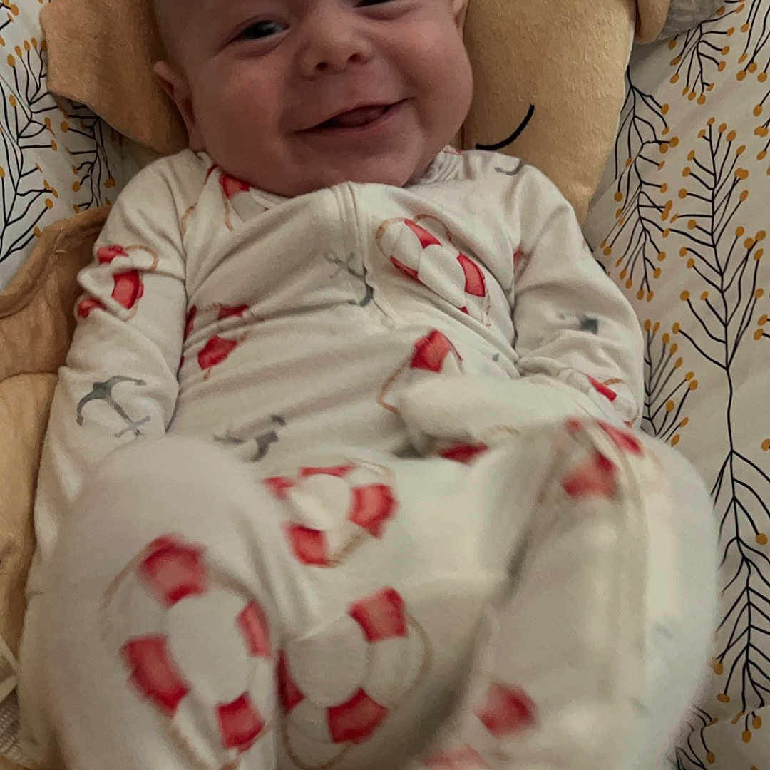 Theo is registered to the contest to win money with this photo: baby, bed, blanket, clothing, couch, cushion, face, furniture, happy, head, homedecor, laughing, newborn, pajamas, person, photography, portrait, quilt, sleeping, smile