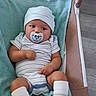 baby, infant, child, pacifier, hat, striped_clothing, onesie, socks, bouncer, baby_chair, indoor, portrait, sitting, lying_down, cozy, turquoise, adult, legs, face, home
