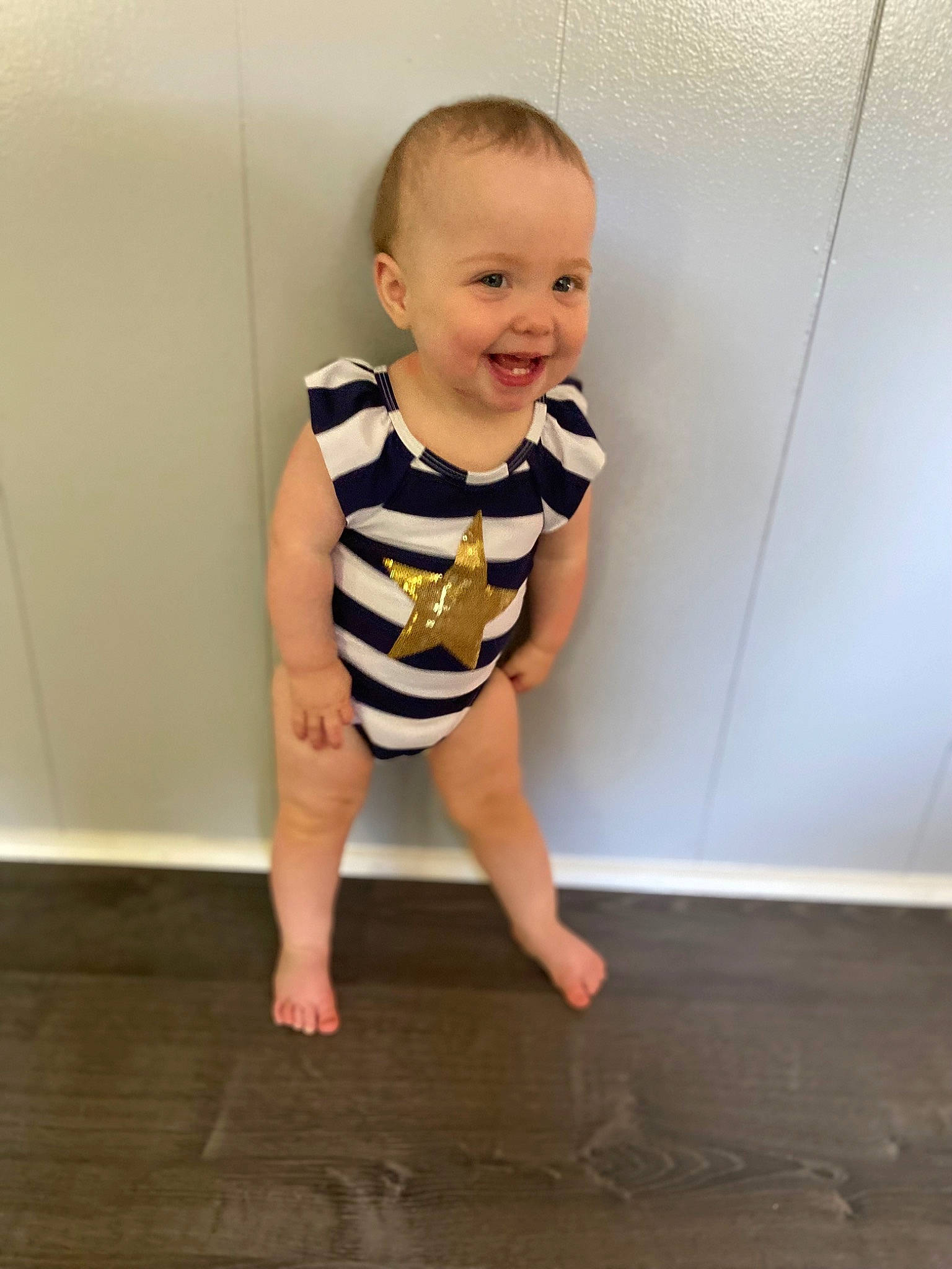 Scarlett joined the competition — help win amazing prizes! baby, baby_toddler_clothing, barefoot, dress, face, floor, flooring, foot, happy, hardwood, human_leg, joy, knee, leg, pattern, person, sleeve, smile, standing, t_shirt