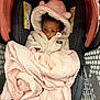 baby, child, car_seat, blanket, hoodie, pink, cream, face, eyes, infant, warm_clothing, cute, indoor, soft_texture, seat, baby_carrier, headwear, curious, wrapped, cozy