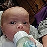 baby, bottle, feeding, milk, infant, person, face, hand, clothing, furniture, drawer, wood, indoor, closeup, newborn, expression, sitting, adult, casual, portrait