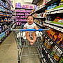 baby, shopping_cart, store, aisle, shelves, products, smiling, child, infant, happy, retail, shopping, floor, clothing, person, grocery, retail_shelf, container, package, indoor