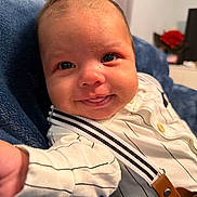 Lorenzo is registered to the contest to win money with this photo: baby, smile, face, infant, clothing, striped_shirt, suspenders, blue_blanket, cute, portrait, indoors, happy, young_child, person, closeup, skin, hand, head, eyes, expression