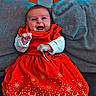 Céleste participe au concours pour gagner de l'argent avec cette photo : baby, child, red_dress, smiling, happy, sitting, couch, cushion, indoors, wooden_backdrop, festive, holiday, clothing, footwear, face, person, portrait, cute, infant, cozy