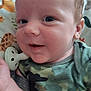 Elyjah is registered to the contest to win money with this photo: baby, infant, smiling, face, eyes, onesie, camouflage, pacifier, blanket, animal_pattern, close_up, skin, head, ear, hand, soft_toys, cute, child, portrait, indoor