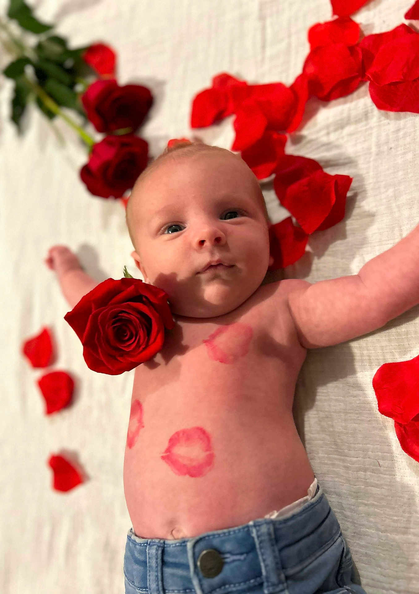 Andréa participe au concours pour gagner de l'argent avec cette photo : baby, infant, newborn, rose, rose_petals, flower, petals, kiss_marks, lipstick, bed, blanket, denim, jeans, shirtless, portrait, closeup, lying_down, face, eyes_open, rosy_cheeks