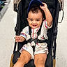 toddler, stroller, child, smiling, cap, clothing, indoor, toy_store, baby, happy, seatbelt, footwear, legs, face, person, retail, shopping, floor, expression, cute