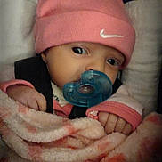 May is registered to the contest to win money with this photo: baby, infant, pacifier, pink_hat, nike_logo, blanket, beanie, car_seat, harness, closeup, face, eyes, hands, cozy, newborn, portrait, dim_lighting, soft_texture, sleepy, adorable
