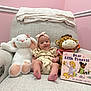 Juliette is registered to the contest to win money with this photo: baby, armchair, plush_toy, stuffed_animal, book, child, pink_wall, headband, smile, feet, cushion, blanket, giraffe, bunny, nursery, indoor, person, clothing, reading, cute