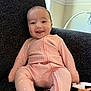 baby, infant, smile, pink_onesie, polka_dot, armchair, blanket, cozy, happy, tongue_out, indoor, child, cute, face, seated, furniture, texture, soft, portrait, relaxed