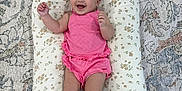 Juliette is registered to the contest to win money with this photo: baby, carpet, child, cushion, cute, face, floral_pattern, footwear, happy, indoors, infant, lying_down, patterned_rug, person, pillow, pink_outfit, skin, small, smiling, sock_booties