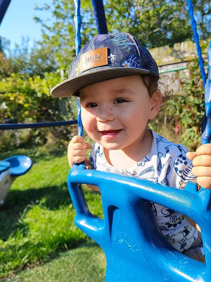 Mayson participe au concours pour gagner de l'argent avec cette photo : baby_toddler_clothing, baseball_cap, blue, cap, child, cool, electric_blue, fun, grass, happy, hat, headwear, human_settlement, joy, leaf, leisure, person, personal_protective_equipment, play, recreation
