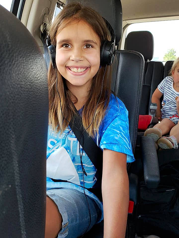 Holly is registered to the contest to win money with this photo: auto_part, car, car_seat, child, driving, family_car, head_restraint, joy, long_hair, luxury_vehicle, passenger, person, seat_belt, sitting, smile, subcompact_car, vacation, vehicle