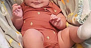 Brian is registered to the contest to win money with this photo: baby, infant, child, smiling, portrait, sitting, indoors, blanket, baby_seat, giraffe_pattern, plush_toy, orange_clothing, white_socks, face, hands, legs, cozy, happy, photography, close_up