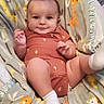 baby, infant, child, smiling, portrait, sitting, indoors, blanket, baby_seat, giraffe_pattern, plush_toy, orange_clothing, white_socks, face, hands, legs, cozy, happy, photography, close_up