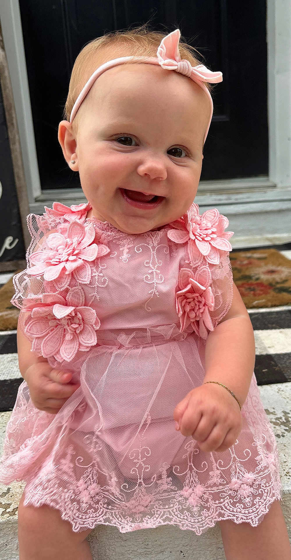 June joined the competition — help win amazing prizes! baby, child, smiling, pink_dress, headband, lace, flower, sitting, happy, cute, portrait, outdoor, doorstep, bracelet, person, infant, young_child, fashion, accessory, front_door