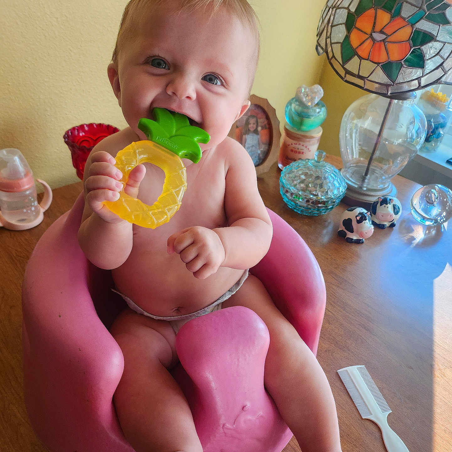 Xoie joined the competition — help win amazing prizes! baby, chewing, child, comb, cow_figurines, cute, decorative_items, glass_containers, happy, indoors, infant, lamp, person, photo_frame, pink_seat, smiling, stained_glass, teether, toy, wooden_table