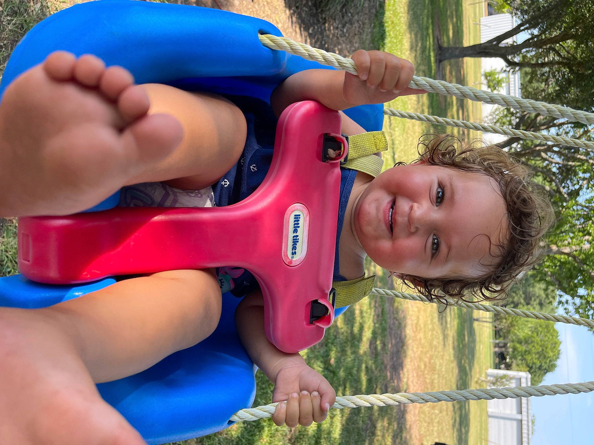 Macie is registered to the contest to win money with this photo: baby_toddler_clothing, blue, child, fun, grass, green, happy, joy, leisure, organ, outdoor_play_equipment, people_in_nature, person, photograph, playground, recreation, smile, summer, toddler, tree