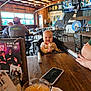 baby, high_chair, smiling, restaurant, wooden_table, drink, phone, people, indoor, ceiling, chairs, tables, wall_art, insulation, window, menu, person, wood, happy, casual