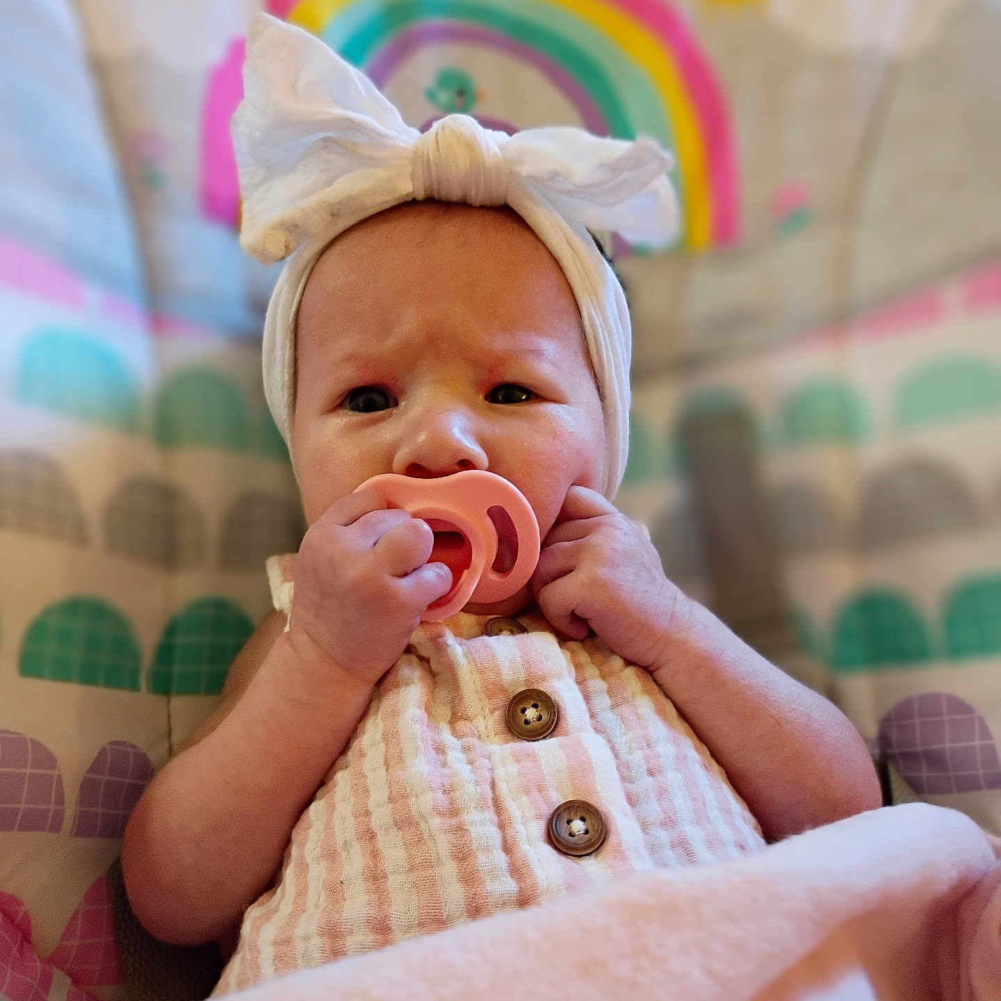 Raelynn is registered to the contest to win money with this photo: baby, pacifier, headband, bow, infant, clothing, blanket, colorful, rainbow, seat, cute, child, portrait, indoors, soft, hand, expression, button, fabric, babywear