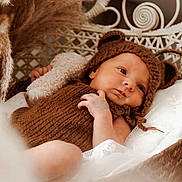Jade participe au concours pour gagner de l'argent avec cette photo : baby, infant, knitted_clothing, brown, bear_hat, wicker_chair, soft_texture, blanket, cute, portrait, indoors, newborn, child, cozy, resting, hand, face, headwear, warm, relaxed