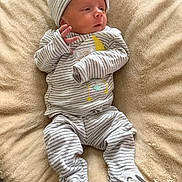 Juan is registered to the contest to win money with this photo: baby, infant, striped_clothing, hat, blanket, soft_texture, footed_pajamas, animal_face, sleepwear, newborn, cute, lying_down, indoors, comfort, small_hands, expression, cozy, child, apparel, resting
