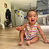 baby, child, smiling, indoor, floor, wooden_floor, striped_clothing, high_chair, kitchen, home, staircase, cabinet, refrigerator, light, person, happy, sitting, infant, cute, portrait