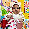 Anastasia is registered to the contest to win money with this photo: baby, infant, child, knit_hat, strawberry_pattern, plush_toy, bunny, cute, puckered_face, colorful_background, play_mat, animal_illustrations, music_notes, soft_toy, indoors, portrait, smiling, hand, clothing, person