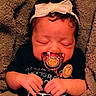 Empress is registered to the contest to win money with this photo: baby, infant, sleeping, pacifier, headband, bow, blanket, portrait, close_up, face, hands, black_clothing, indoors, cozy, newborn, resting, jewelry, sparkle, candid, child