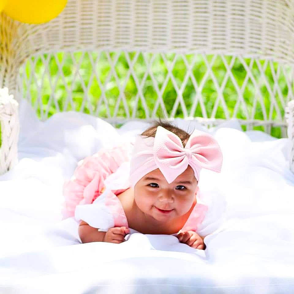 Jaeda is registered to the contest to win money with this photo: baby, baby_toddler_clothing, bedding, comfort, flower, happy, headband, headpiece, headwear, linens, orange, pattern, peach, person, petal, product, room, smile, sweetness, textile
