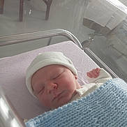 Nathan participe au concours pour gagner de l'argent avec cette photo : newborn, baby, sleeping, hospital, bassinet, blanket, hat, infant, cozy, bed, child, peaceful, resting, indoor, soft_light, knitted, portrait, person, healthcare, quiet