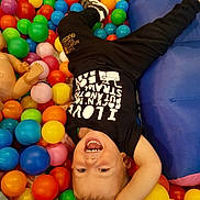 Trent joined the competition — help win amazing prizes! toddler, child, ball_pit, colorful_balls, laughing, upside_down, black_shirt, black_pants, indoor, play, fun, happy, smiling, cushion, plastic_balls, casual_clothing, young_child, joyful, play_area, active