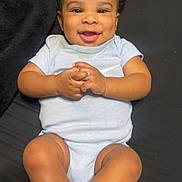 Arcangel is registered to the contest to win money with this photo: baby, smiling, curly_hair, onesie, infant, hands, legs, feet, black_background, happy, cute, child, skin, portrait, lying_down, infant_clothing, playful, dimples, young_child, indoors