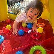 Lucas is registered to the contest to win money with this photo: toddler, child, smiling, indoor, play_area, colorful, balls, rings, toy, crawling, happy, face, hair, floor, blanket, clothing, person, playtime, fun, bright