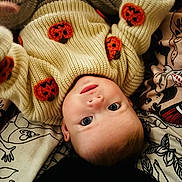 Ivy is registered to the contest to win money with this photo: baby, child, infant, sweater, knitwear, pumpkin, orange, cream, face, eyes, lying_down, blanket, pattern, cute, cozy, soft, portrait, indoors, person, young