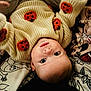 baby, child, infant, sweater, knitwear, pumpkin, orange, cream, face, eyes, lying_down, blanket, pattern, cute, cozy, soft, portrait, indoors, person, young