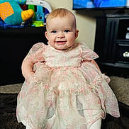 Ivy joined the competition — help win amazing prizes! baby, child, dress, floral, smile, indoor, blanket, toy, television, carpet, cute, sitting, person, happy, infant, white_tights, furniture, living_room, portrait, colorful