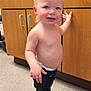 child, toddler, baby, clinic, medical_office, cabinet, countertop, blond_hair, standing, smile, shirtless, diaper, jeans, shoes, floor, handles, portrait, happy, cute, person