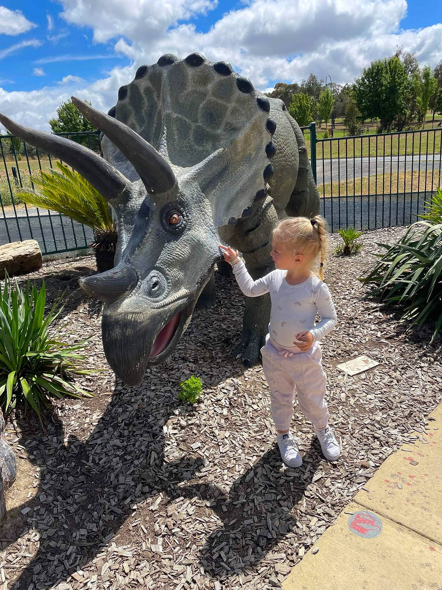 Serayah is registered to the contest to win money with this photo: adaptation, art, automotive_tire, automotive_wheel_system, cloud, fun, garden, grass, landscape, metal, person, plant, sculpture, sky, soil, spring, statue, toddler, tree, triceratops