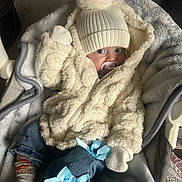 Havana is registered to the contest to win money with this photo: baby, infant, pacifier, hat, pom_pom, jacket, fuzzy_clothing, mittens, denim_pants, blue_ribbons, baby_seat, blanket, socks, carpet, indoor, cozy, cute, child, portrait, warm_clothing