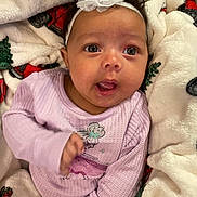 Maddie joined the competition — help win amazing prizes! baby, infant, headband, flower, purple_clothing, blanket, holiday_pattern, cozy, cute, indoors, child, person, smile, expression, portrait, young_child, soft_texture, warm, candid, happy